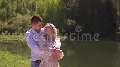 可爱的夫妇拥抱在湖畔，拥抱。 漂亮的家伙和女孩站在一个拥抱上
